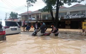 Seorang personel Polresta Samarinda tampak membantu warga yang terjebak banjir. (foto : Exclusive)