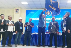 Akhmad Munir mengibarkan Bendera Pataka PWI Pusat setelah dinobatkan sebagai Ketua Umum PWI Pusat periode 2025–2030, usai meraih dukungan 52 suara mengalahkan jumlah perolehan suara Hendry Ch. Bangun yang hanya meraih 35 suara. (foto: Exclusive)